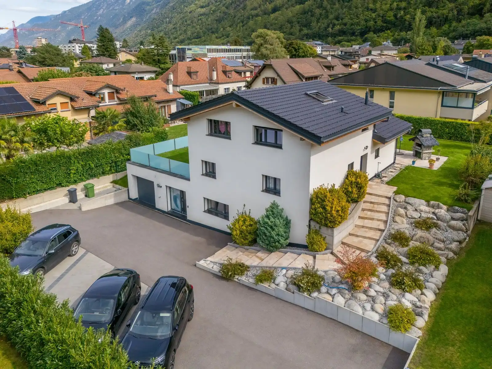 Une villa vue de trois quarts, allée pavée et jardin arboré