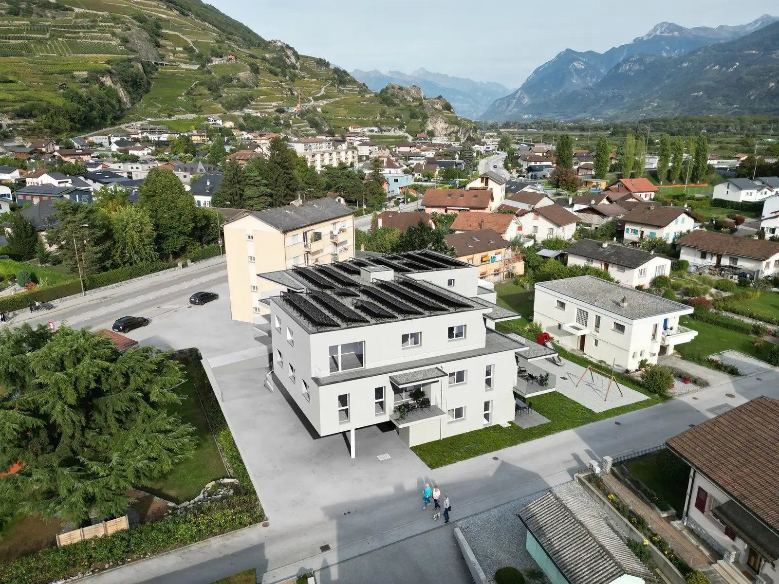 Un immeuble locatif en Valais, vu du ciel, avec la vallée du Rhône derrière
