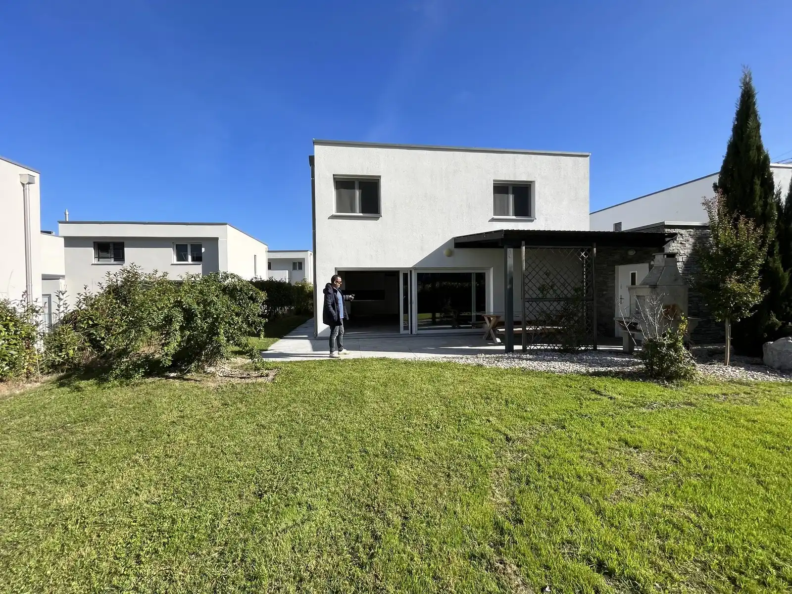 Une villa contemporaine avec son couvert et sa pelouse, en fin de journée